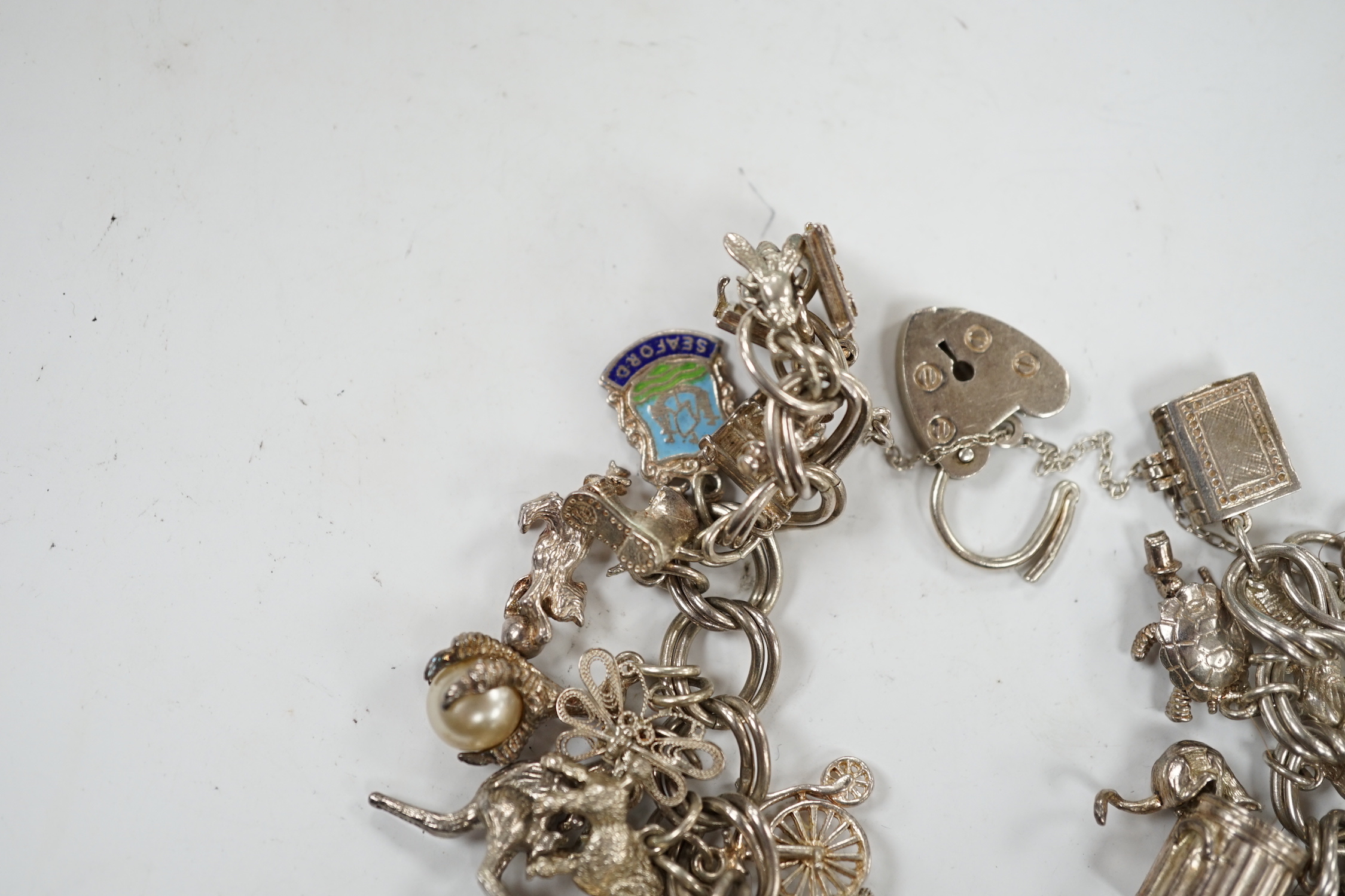 A 1970's silver charm bracelet, hung with assorted charms including birdcage, abacus, piglet, etc. and another silver charm bracelet with loose charms.